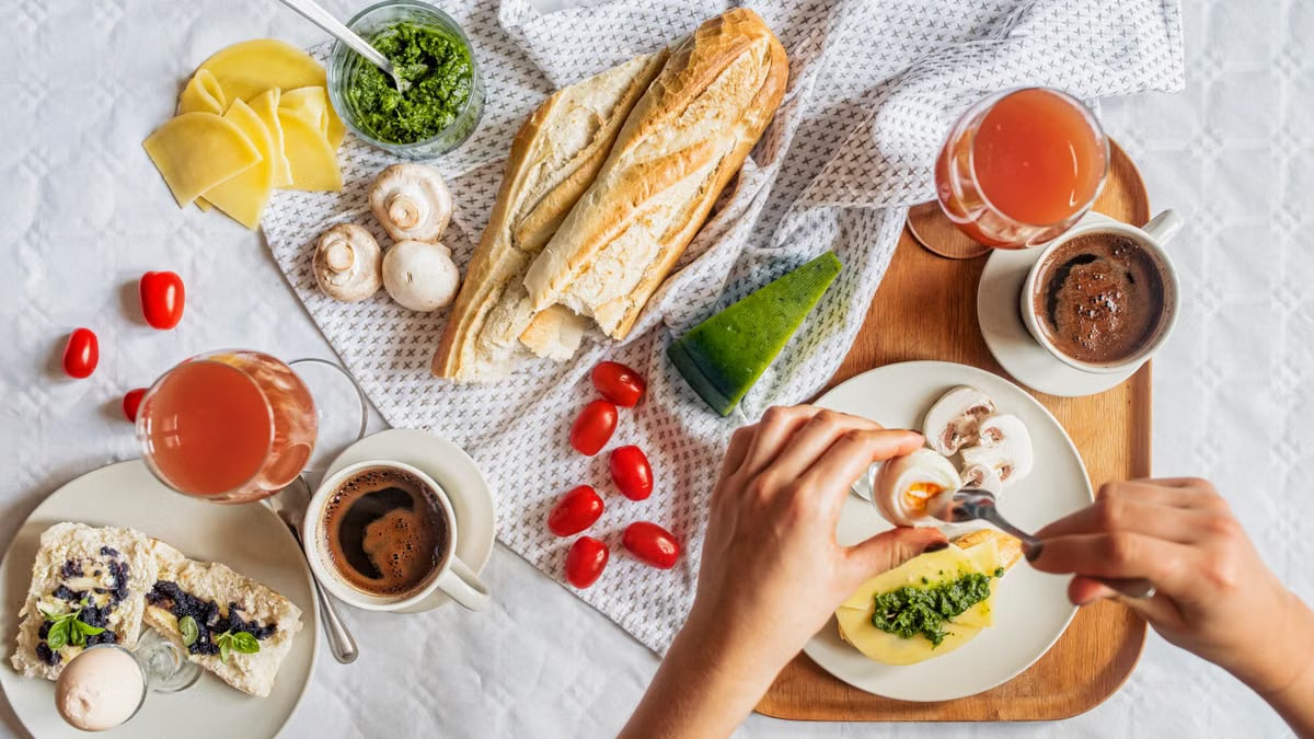 Overhead shot of a delicious breakfast flatlay featuring fresh ingredients and coffee on a white tablecloth.
